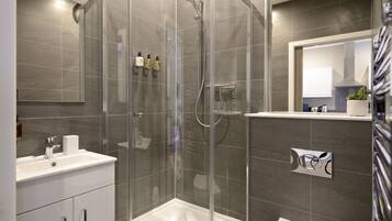 A modern bathroom with a glass-enclosed shower, a white sink, and a mirror above the sink.