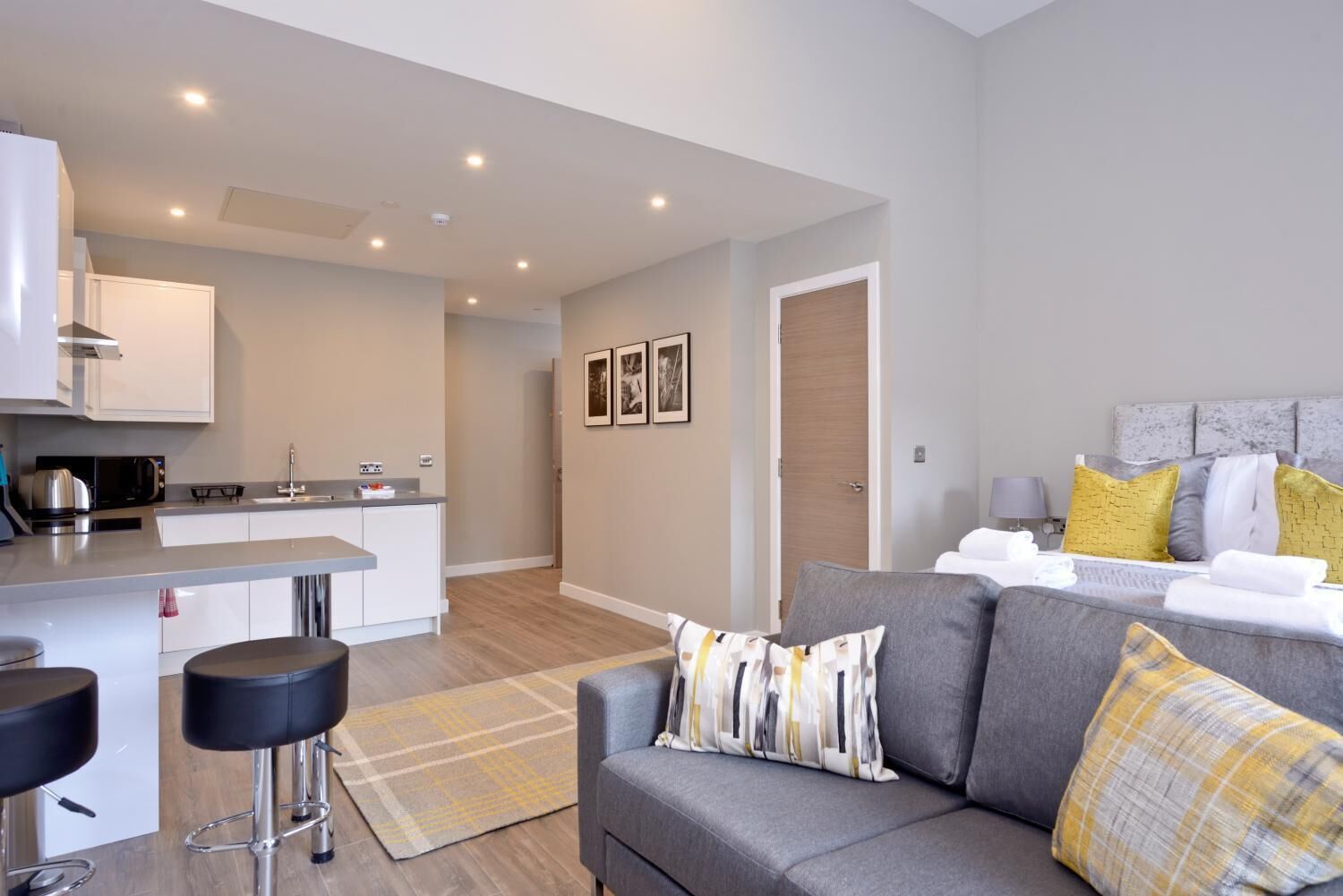 A modern apartment with a kitchen, dining area, and a living room with a sofa and a bed.