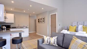 A modern apartment with a kitchen, dining area, and a living room with a sofa and a bed.
