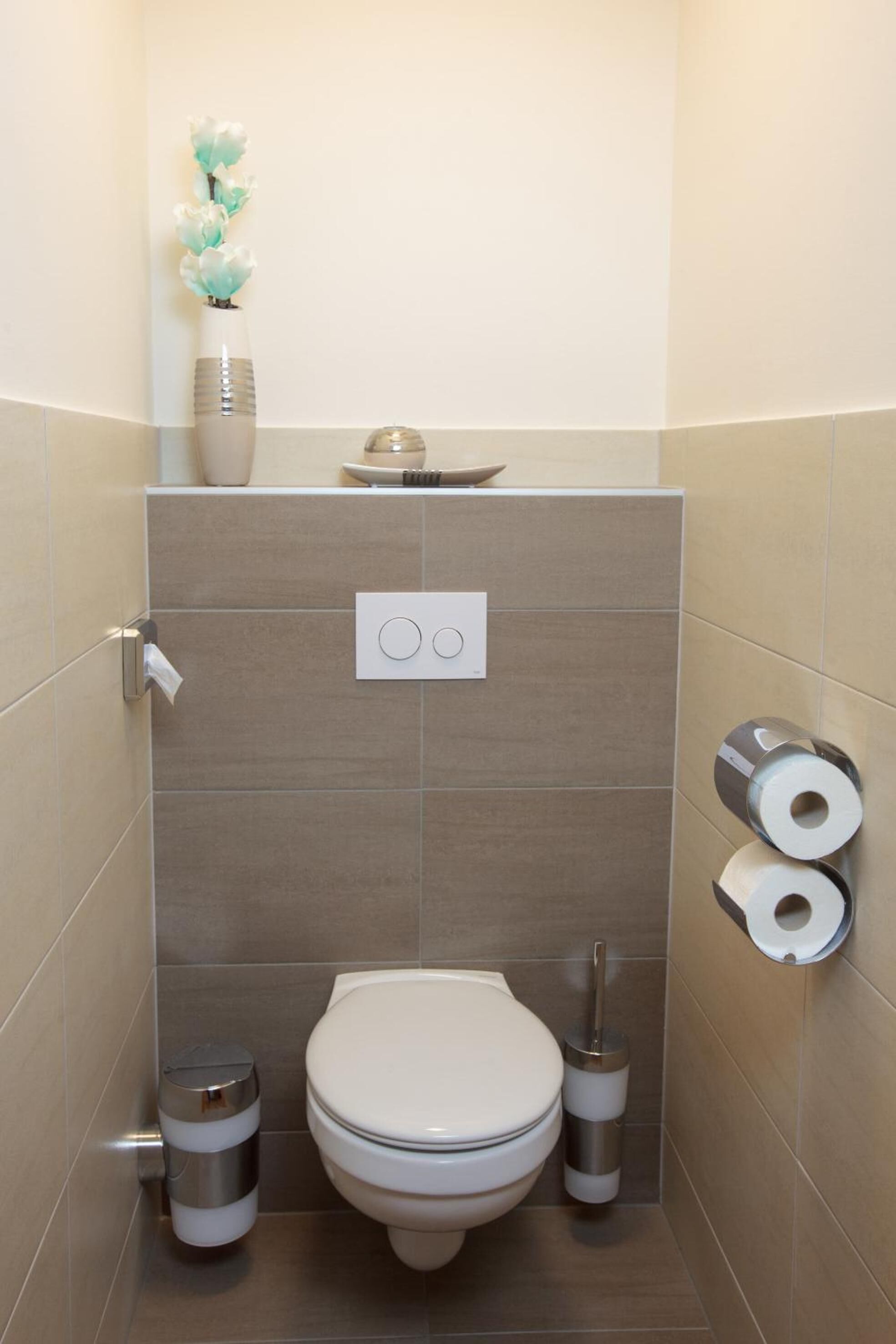 A modern bathroom with a toilet, bidet, and toilet paper holder.