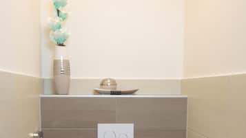 A modern bathroom with a toilet, bidet, and toilet paper holder.