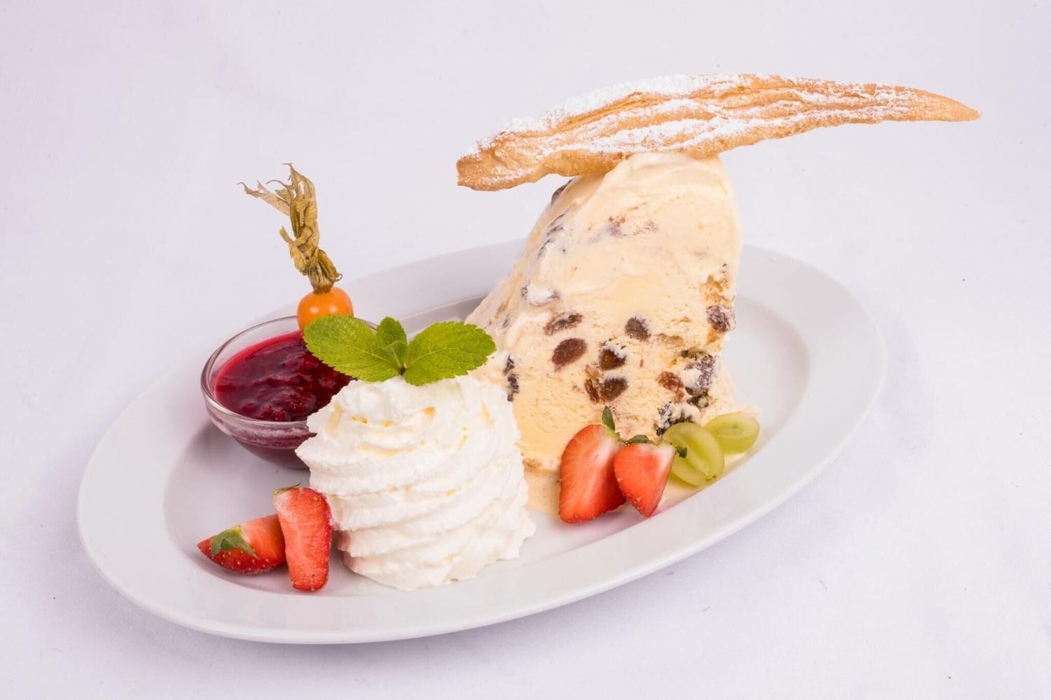 A dessert plate with ice cream, strawberries, grapes, and a piece of cake.