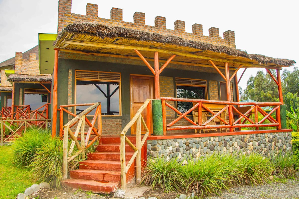 A rustic building with a thatched roof, wooden stairs, and a stone wall.