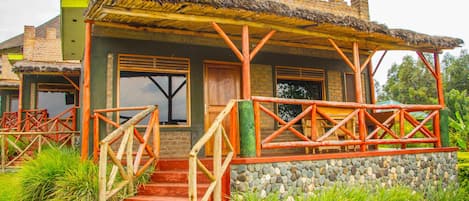 A rustic building with a thatched roof, wooden stairs, and a stone wall.