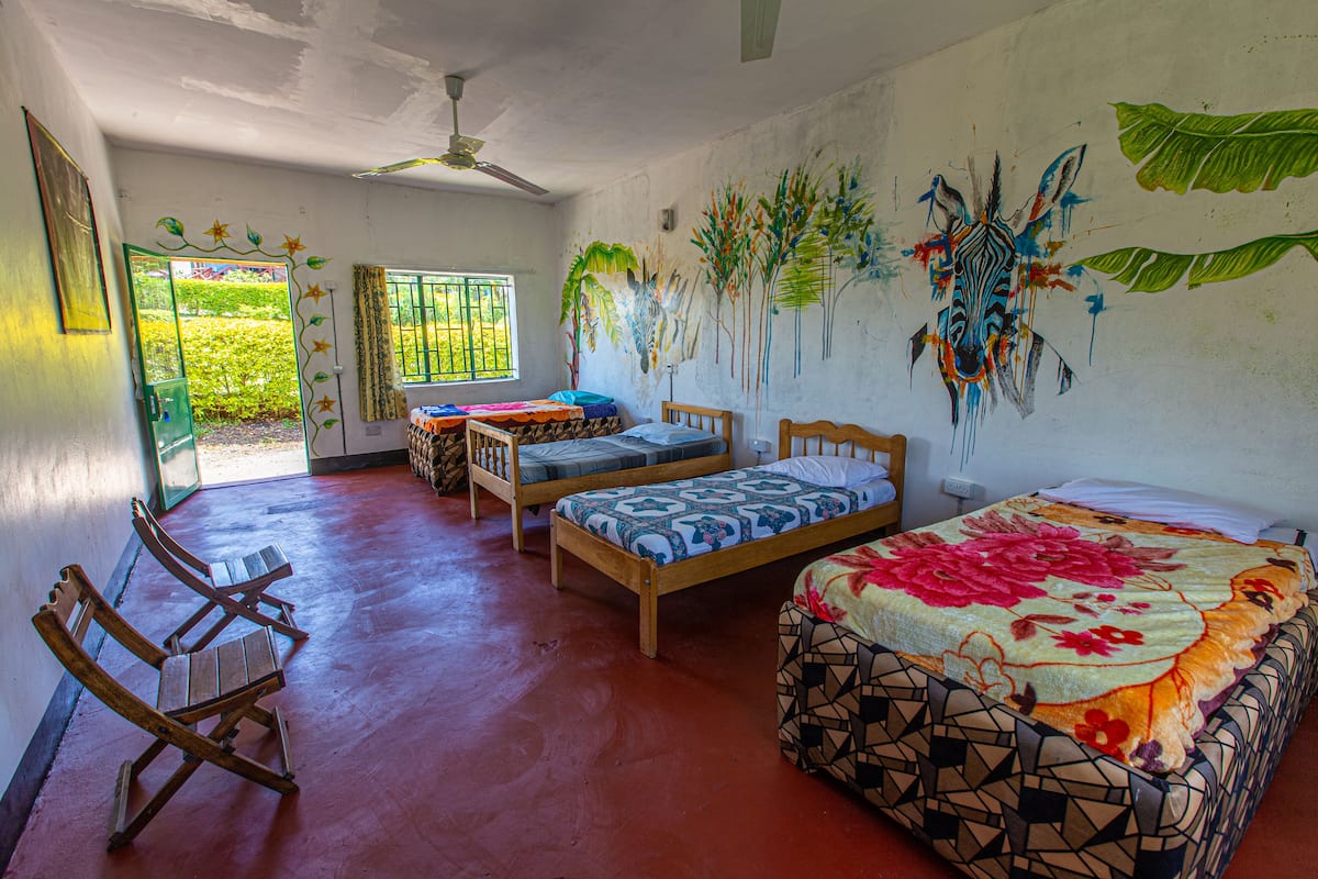 A room with two wooden beds, a bench, and a ceiling fan.
