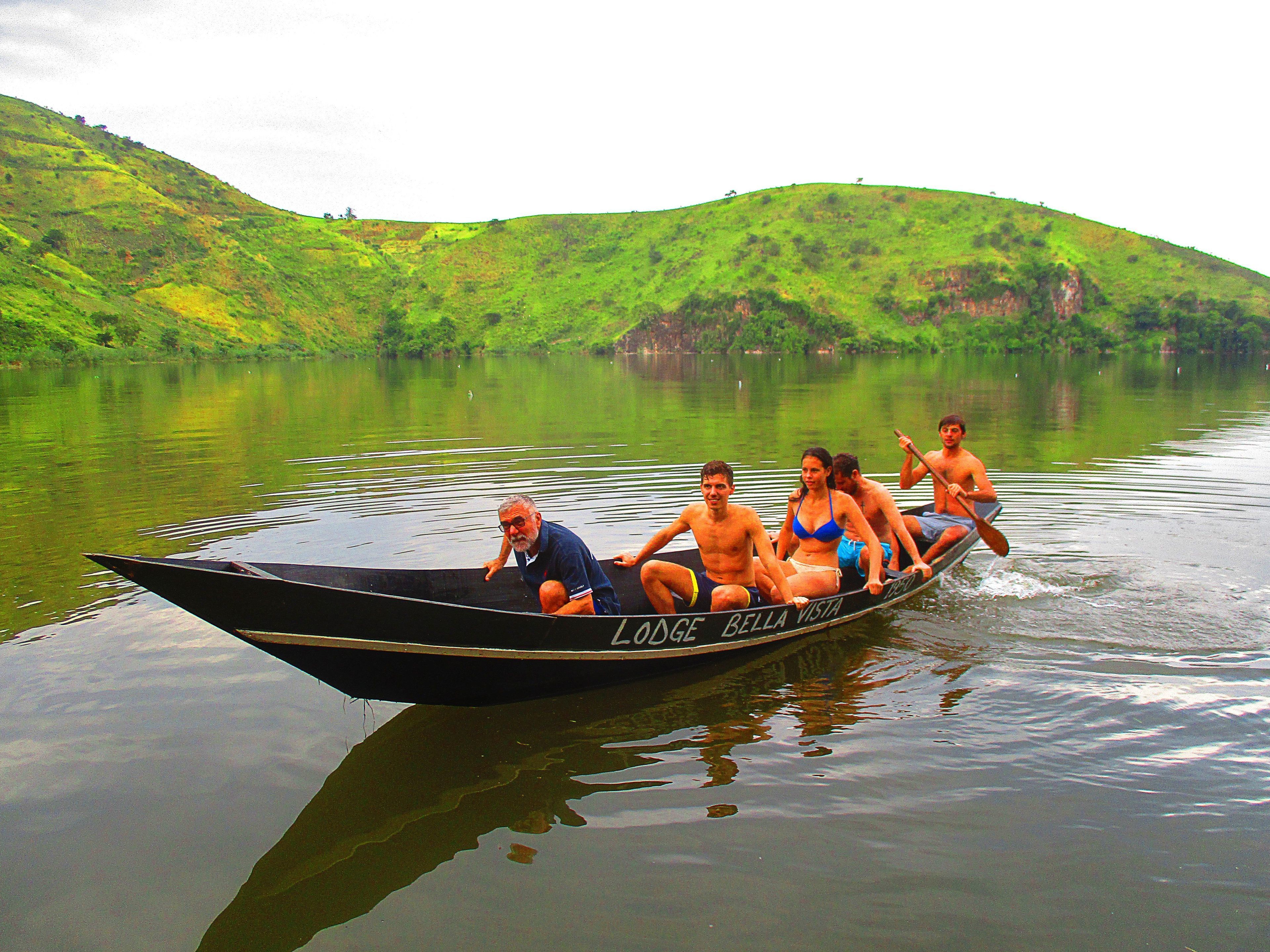 Un bateau avec cinq personnes à bord, naviguant sur une rivière paisible, entourée de collines verdoyantes.