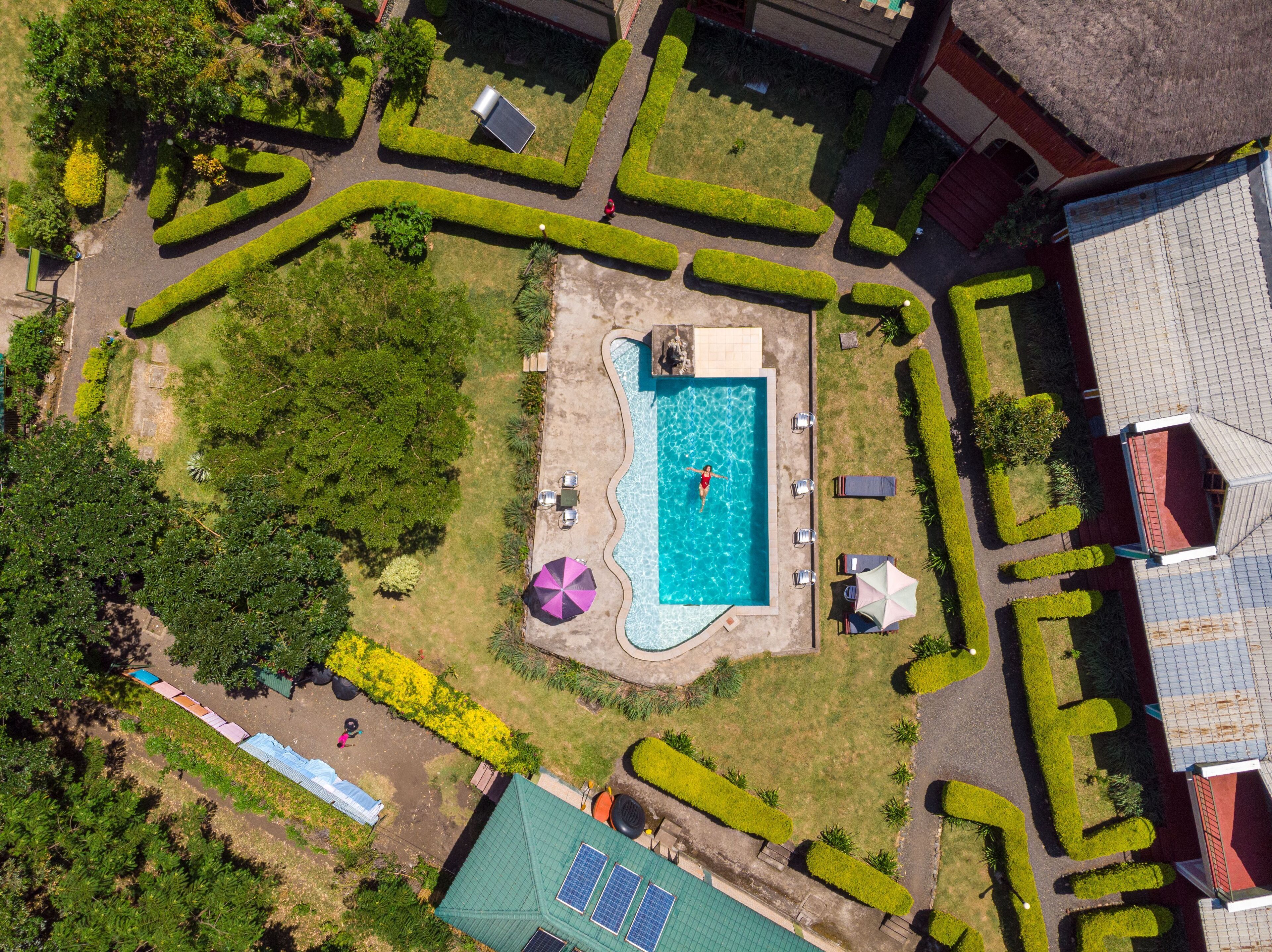 An aerial view of a residential property with a swimming pool, solar panels, and a well-maintained garden.