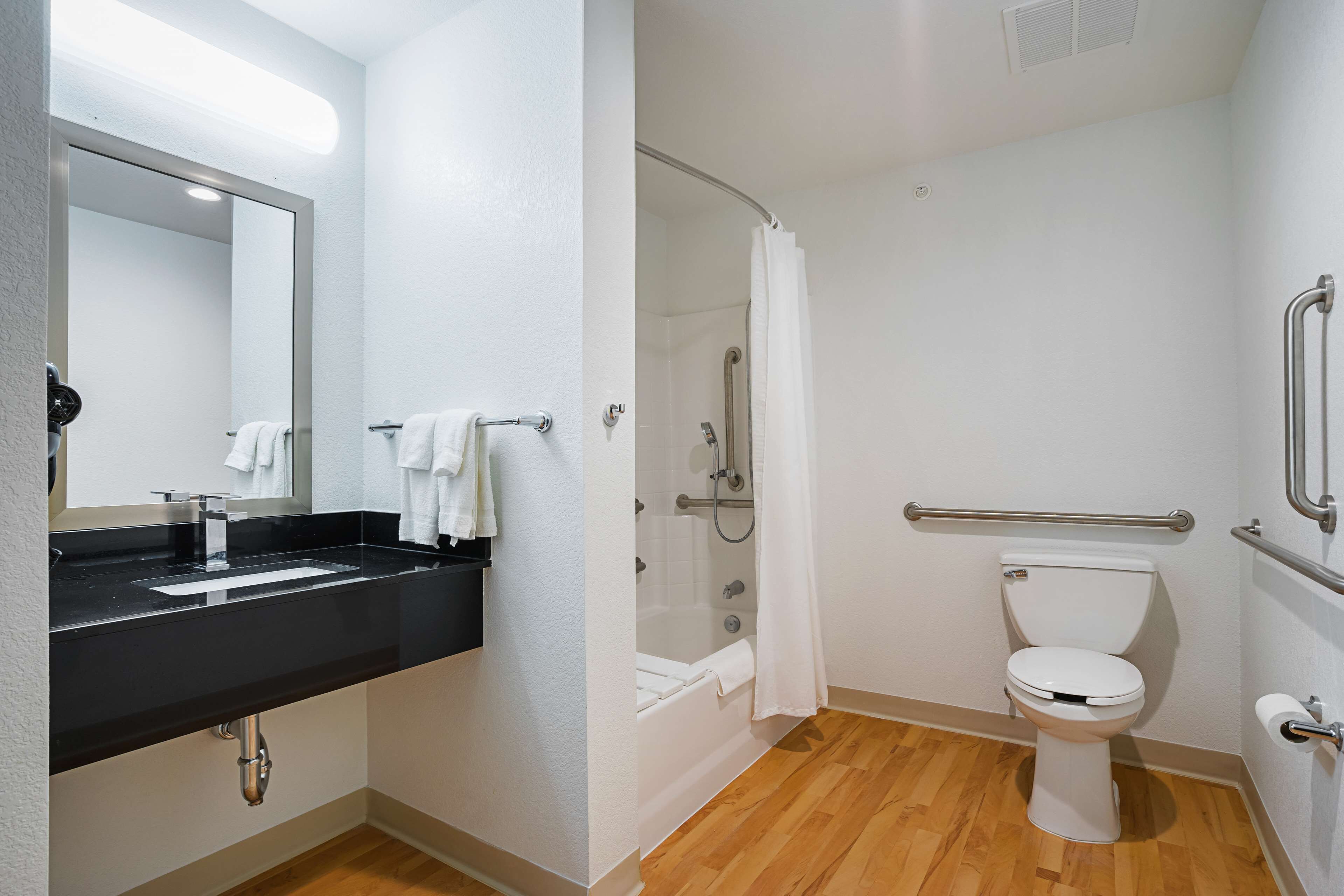 A bathroom with a black sink, white toilet, and a glass-enclosed shower.