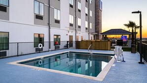An outdoor swimming pool with a clear view of a hotel building in the background. - Studio 6 Buda, TX (Buda)