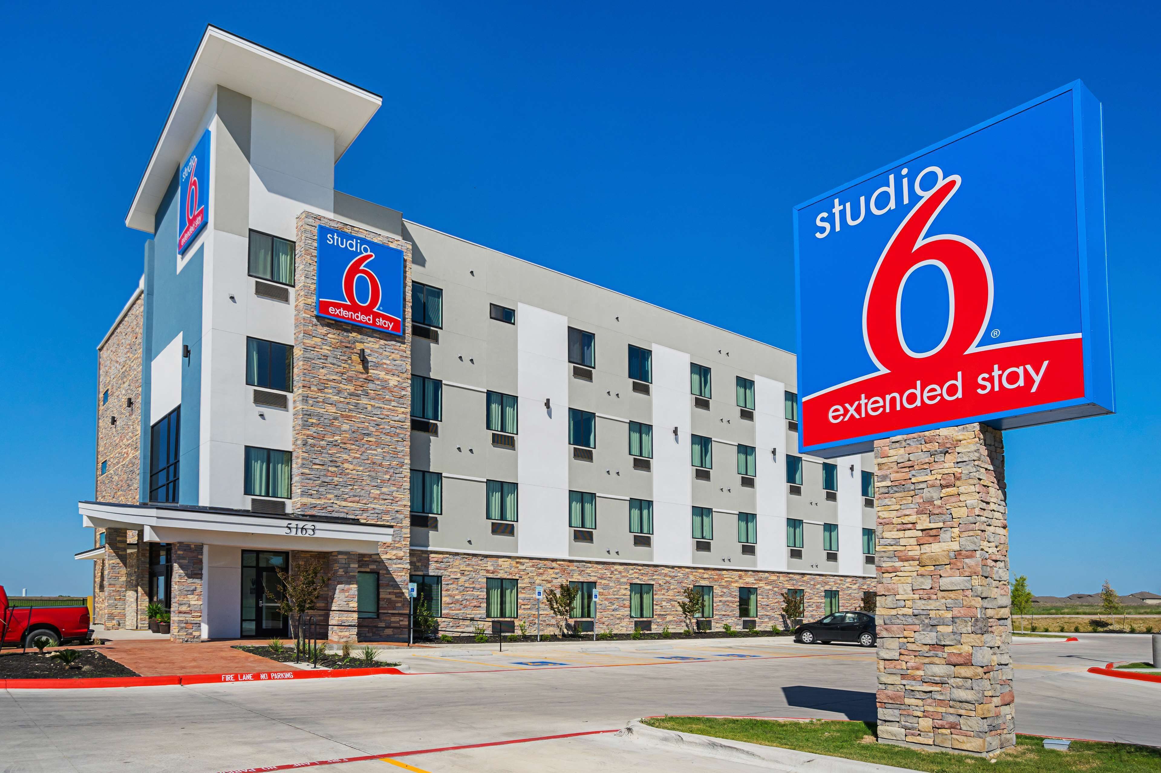 A modern hotel with a stone facade, multiple balconies, and a prominent 'Studio 6 Extended Stay' sign.