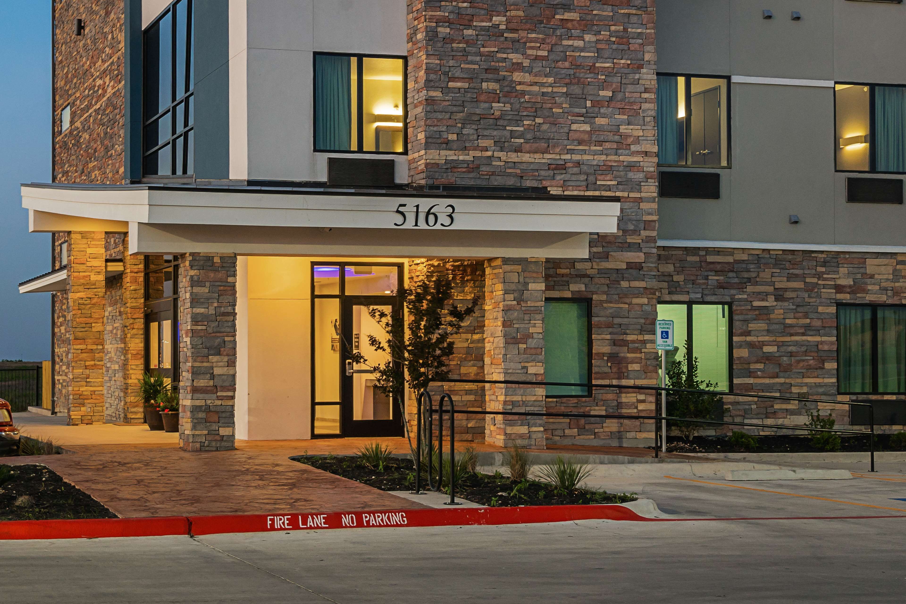 A modern building with a stone facade, numbered 5163, featuring a fire lane and no parking sign.