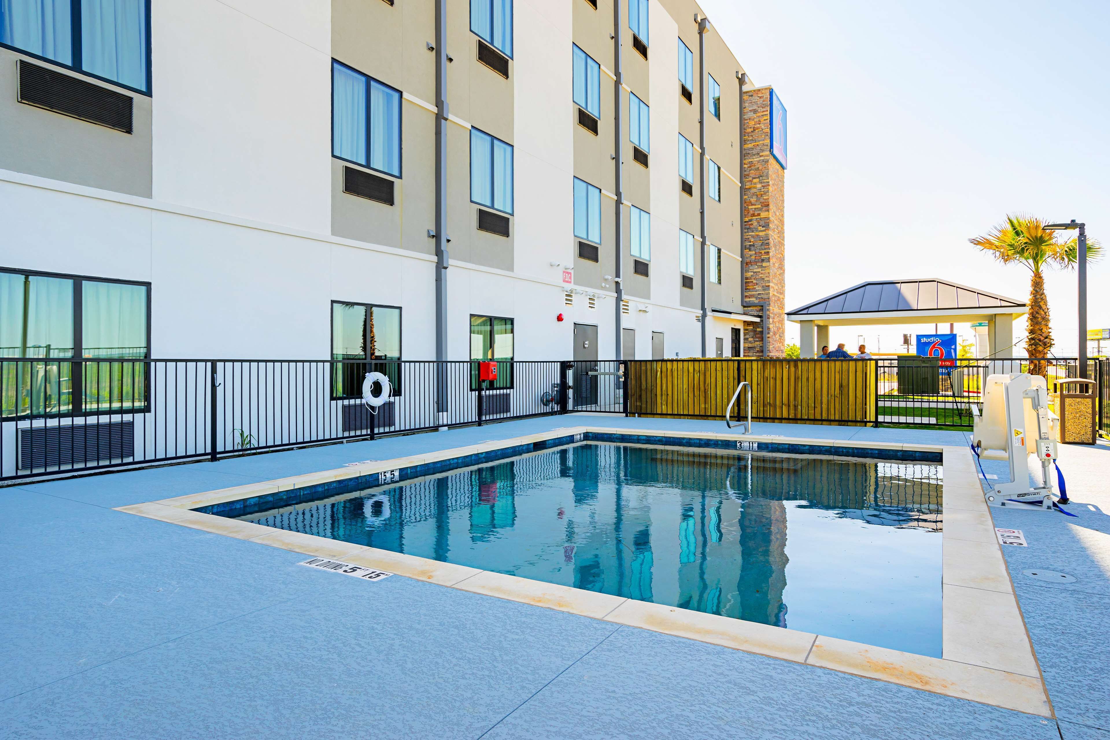A rectangular outdoor pool with a clear blue water surface, surrounded by a low black metal fence.