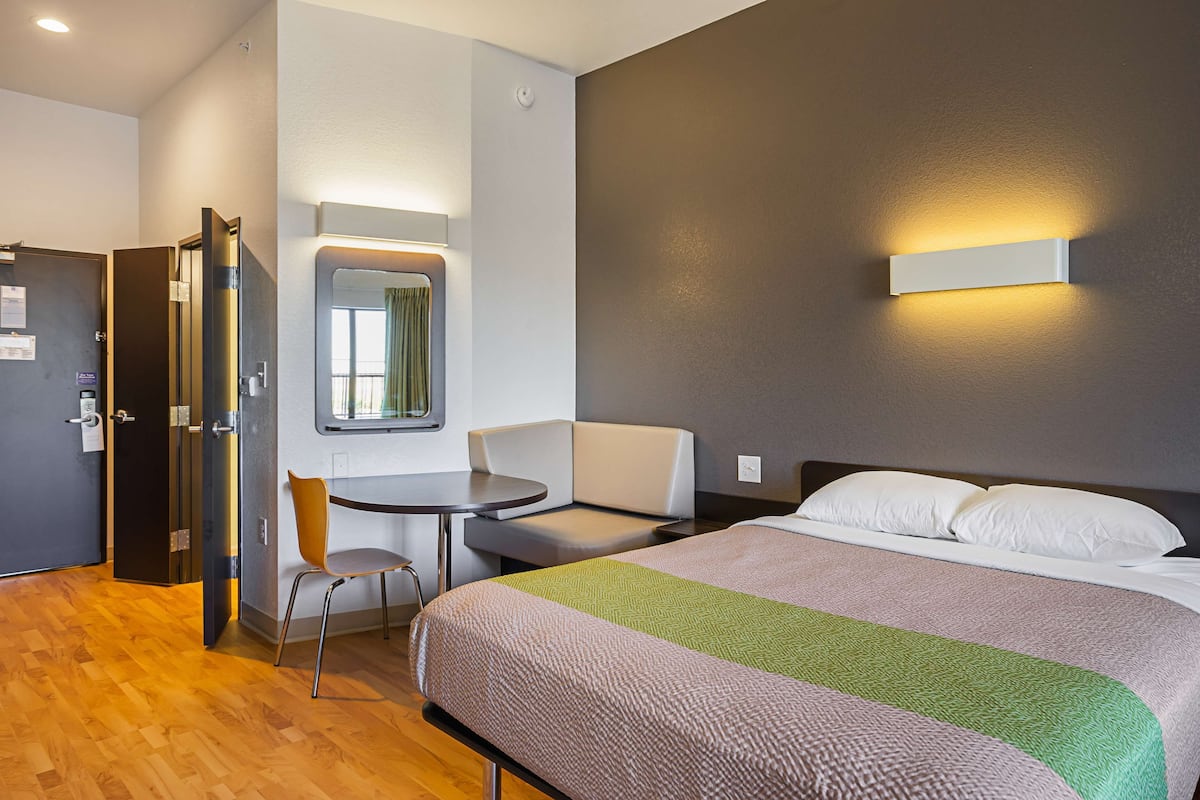 Una habitación de hotel con una cama, un escritorio, una silla y una puerta.
