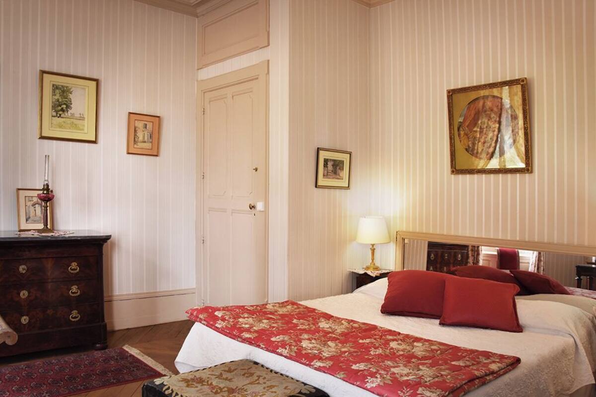 Ein Hotelzimmer mit Bett, Schminktisch, Nachttisch und Tür.