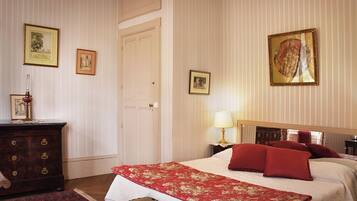 Una habitación de hotel con una cama, un aparador, una mesita de noche y una puerta.
