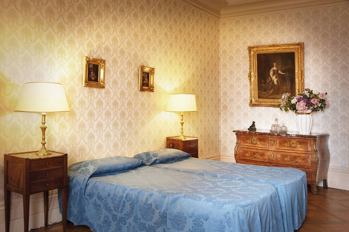 Ein Schlafzimmer mit einem großen Bett, zwei Nachttischen mit Lampen, einer Kommode und zwei gerahmten Bildern an der Wand.