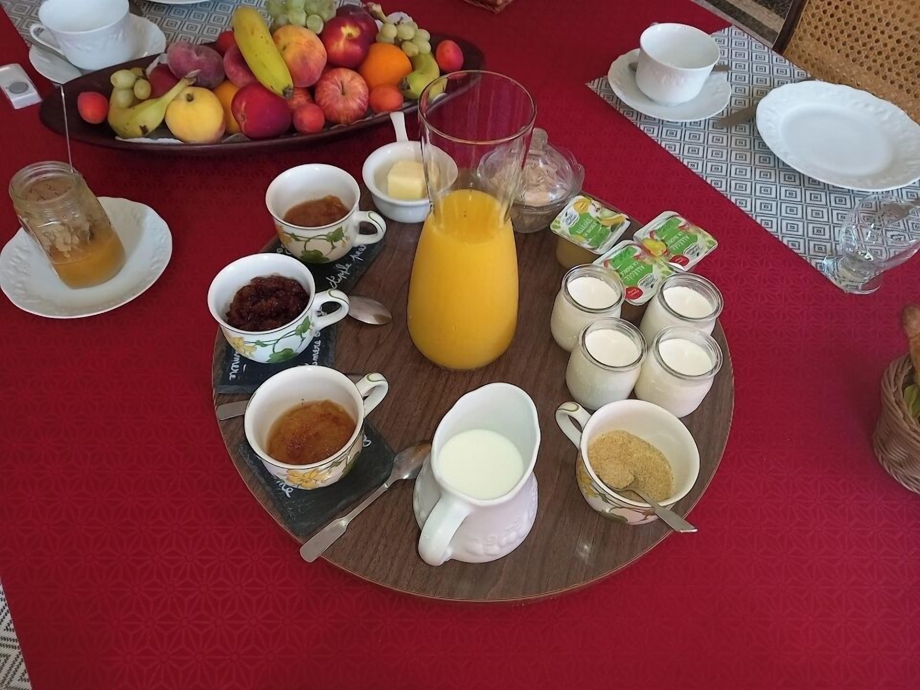 A breakfast table with a variety of food items including fruits, beverages, and condiments.