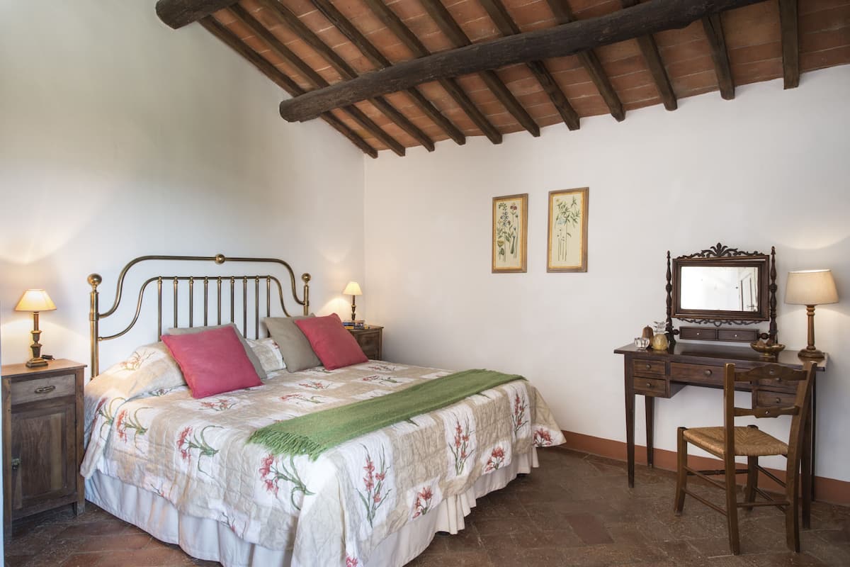 A bedroom with a bed, bedside tables, a desk, and a chair.