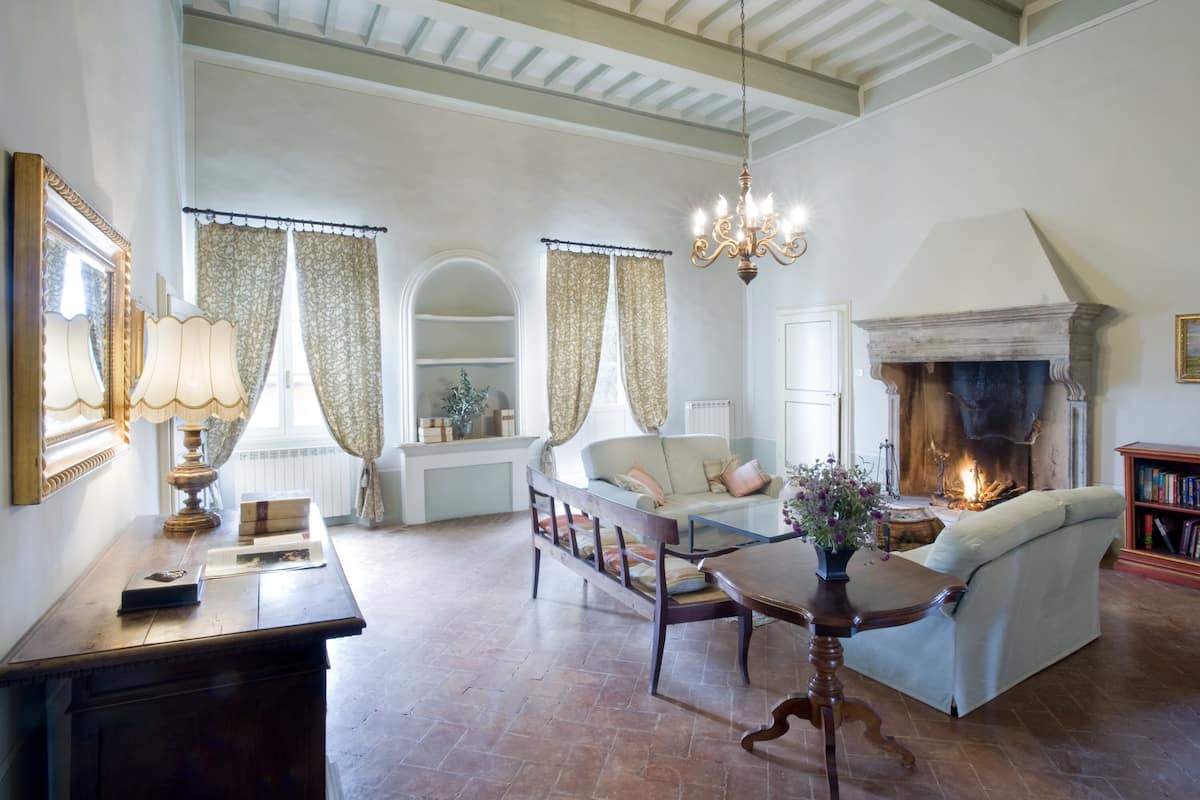 A spacious living room with a fireplace, a sofa, a coffee table, and a bookshelf.