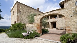 A stone building with a courtyard, a covered archway, and a gravel path leading to a seating area.