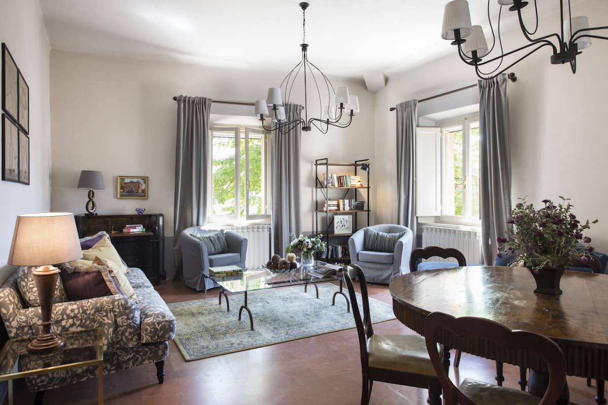 A living room with a sofa, armchairs, a coffee table, a dining table, and a chandelier.