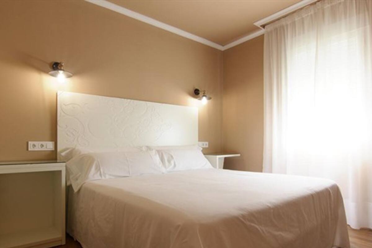 Ein Schlafzimmer mit einem großen Bett, zwei Nachttischen und einem Kopfteil mit Wandleuchten.