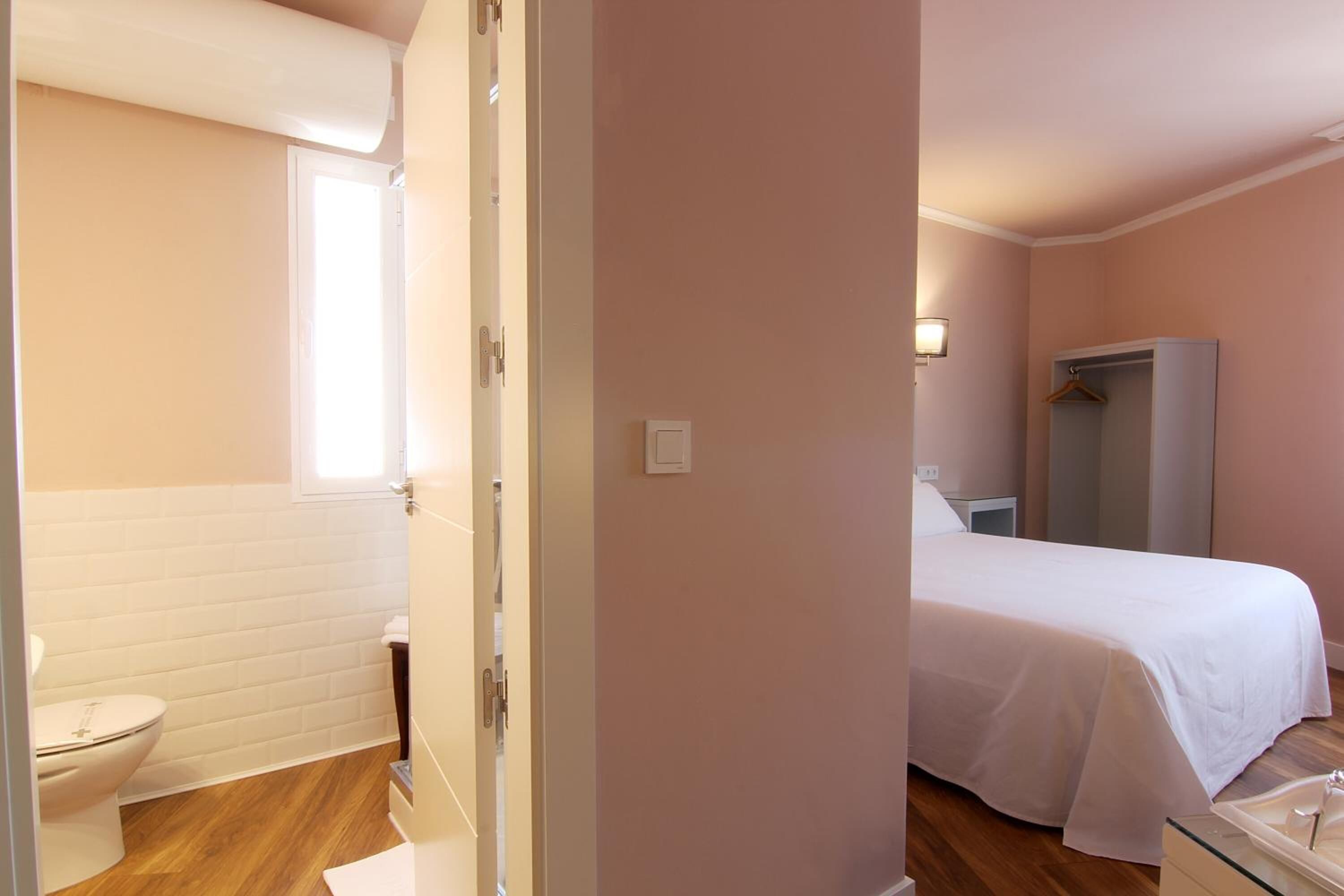 Un dormitorio con cama, armario y baño con inodoro y lavabo.