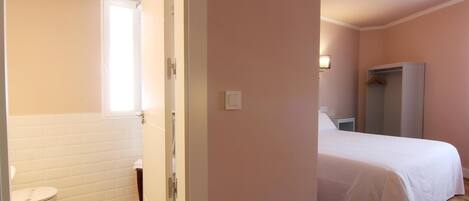 Un dormitorio con cama, armario y baño con inodoro y lavabo.