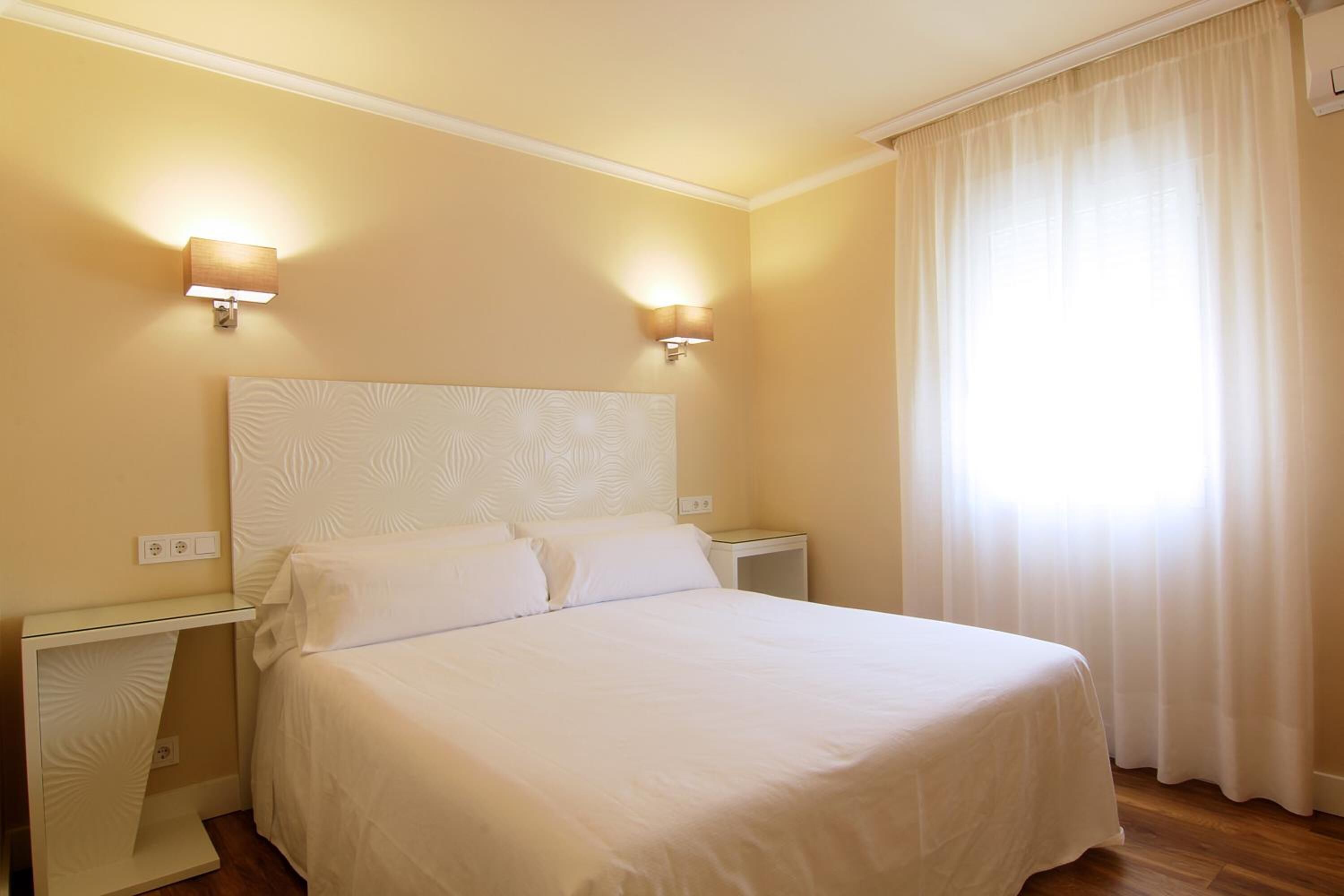Una habitación de hotel con una cama grande, dos mesitas de noche y una mesilla.