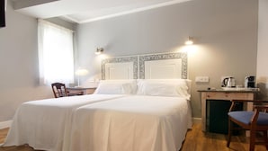 A double bed with a decorative headboard, a desk with a coffee maker, and a chair. - Hostal los Castañuelos (Candeleda)