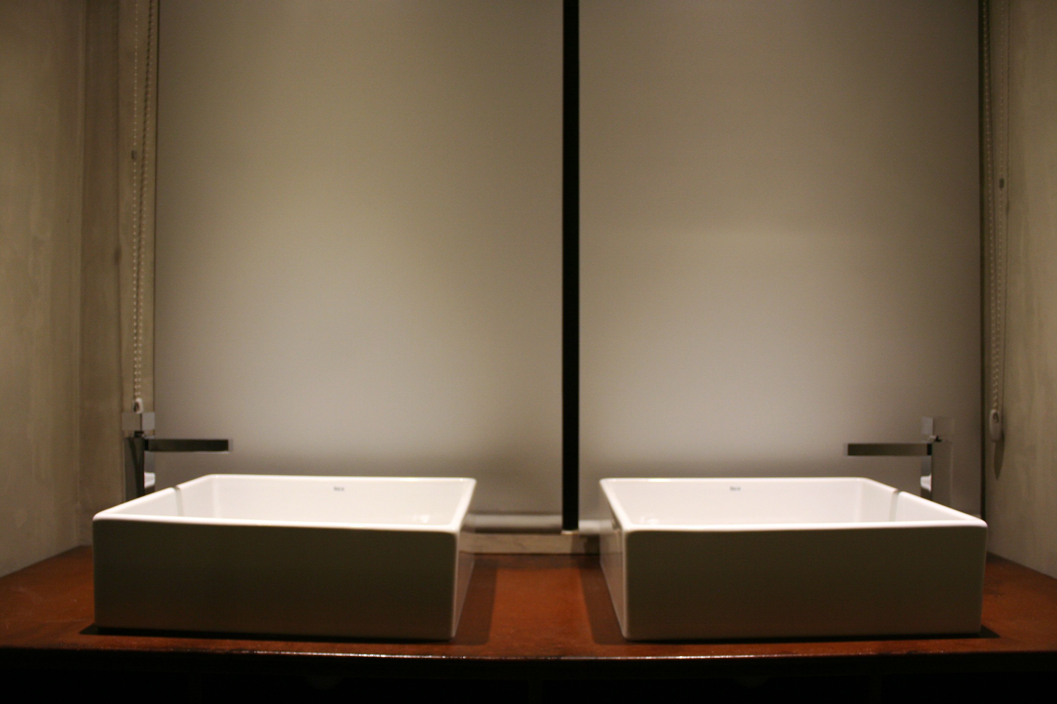 Un baño con dos lavamanos blancos y rectangulares sobre una encimera de madera.