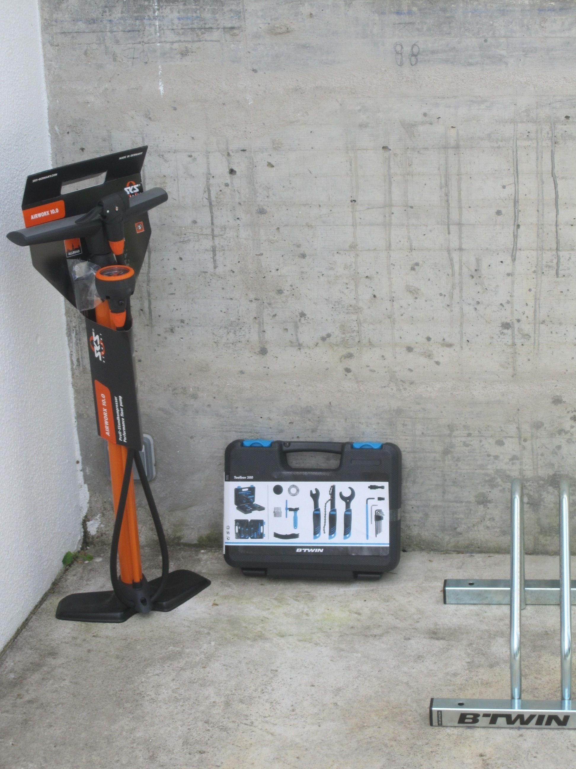A concrete wall corner with a tool chest labeled "Toolbox 500" and a B'TWIN tool stand.
