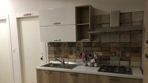 Une cuisine de taille réduite, équipée d’un évier, d’une cuisinière et de meubles de rangement en bois.