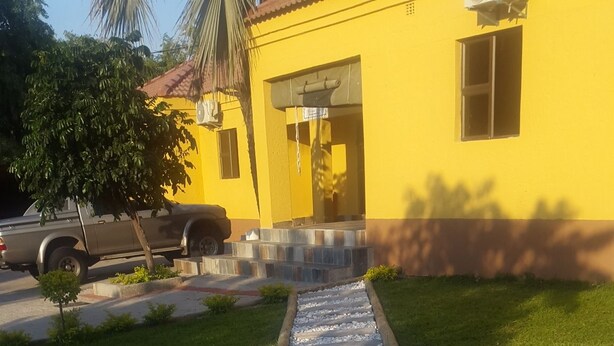 A pathway leading to a yellow building with a tiled entrance.