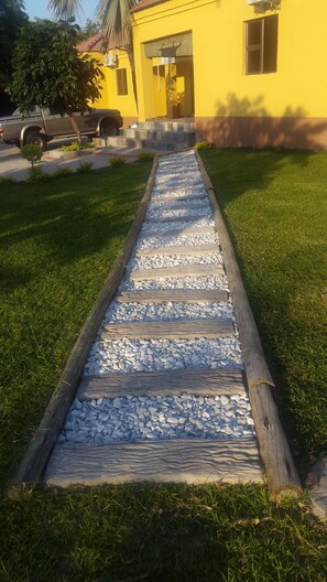 A pathway leading to a yellow building with a tiled entrance. - Maun Executive Inn (Maun)