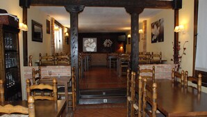 A dining area with wooden tables and chairs, a brick wall, and a fireplace.