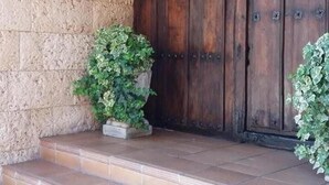 A wooden door with a metal handle, flanked by two lantern-style lights.