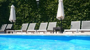 A swimming pool with lounge chairs and umbrellas.