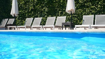 Una piscina al aire libre, sillones reclinables de piscina