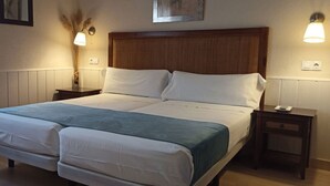 A double bed with a wooden headboard, two bedside tables, and wall-mounted lamps.