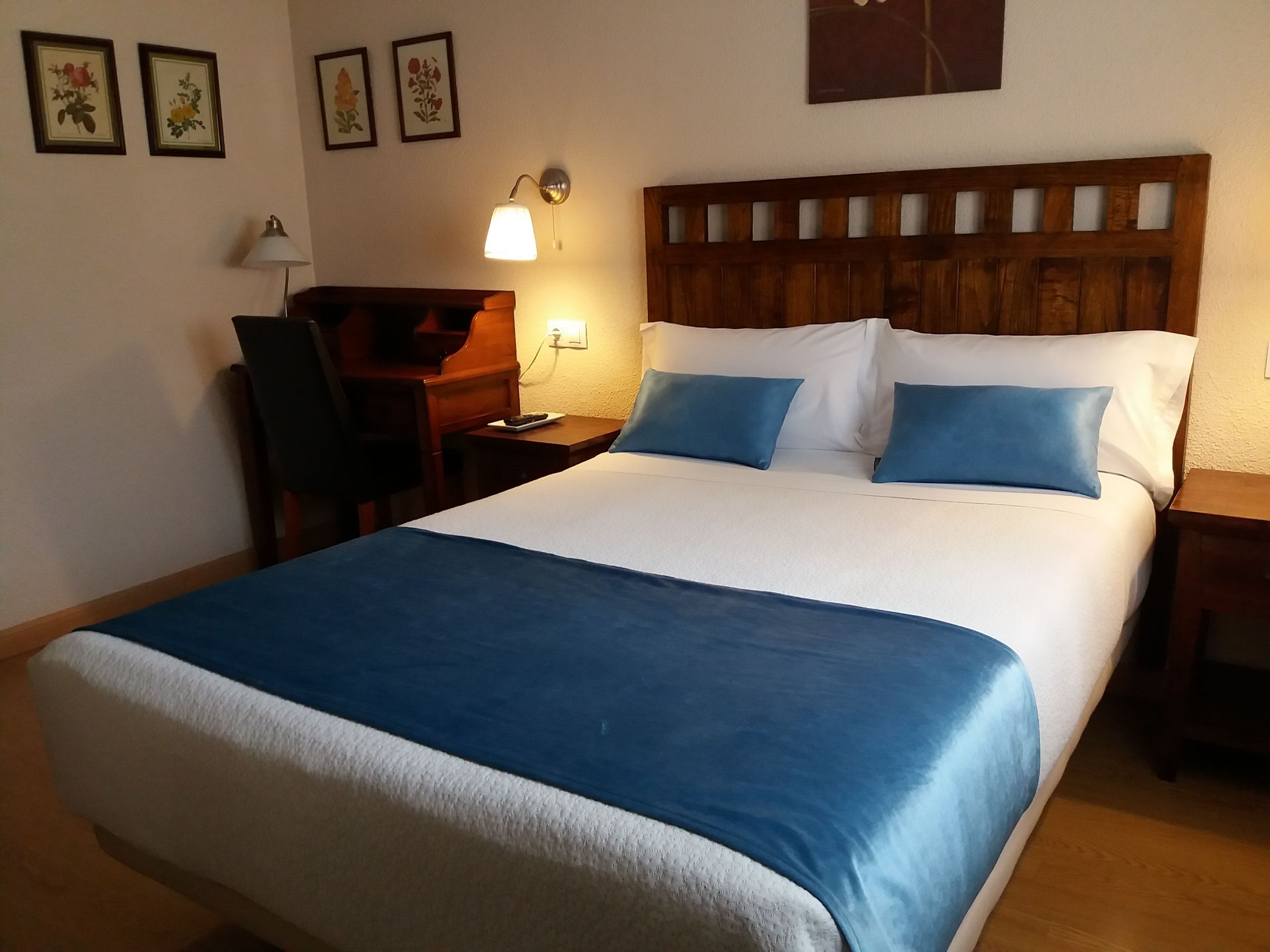 A hotel room with a large bed, a desk, a chair, and a lamp.