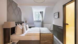 Une chambre d’hôtel moderne dotée d’un grand lit, d’une table de chevet, d’une lampe et offrant une vue sur la ville, ainsi que d’une porte coulissante.