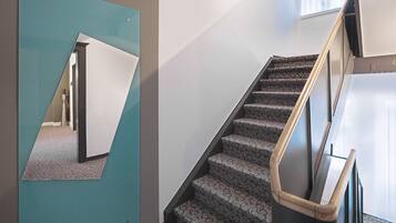 A modern interior with a staircase, a mirrored wall, and patterned carpet.