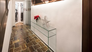 Un couloir avec une étagère en verre, une décoration en forme d’étoile et un tableau encadré accroché au mur.