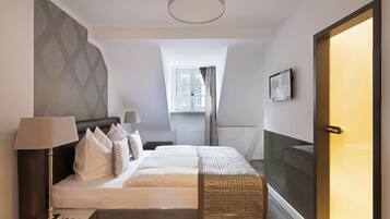 Een hotelkamer met een bed, nachtkastje, lamp en uitzicht op de stad.
