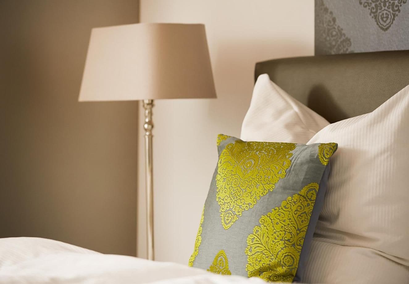 A neatly made bed with a pillow featuring a geometric pattern.