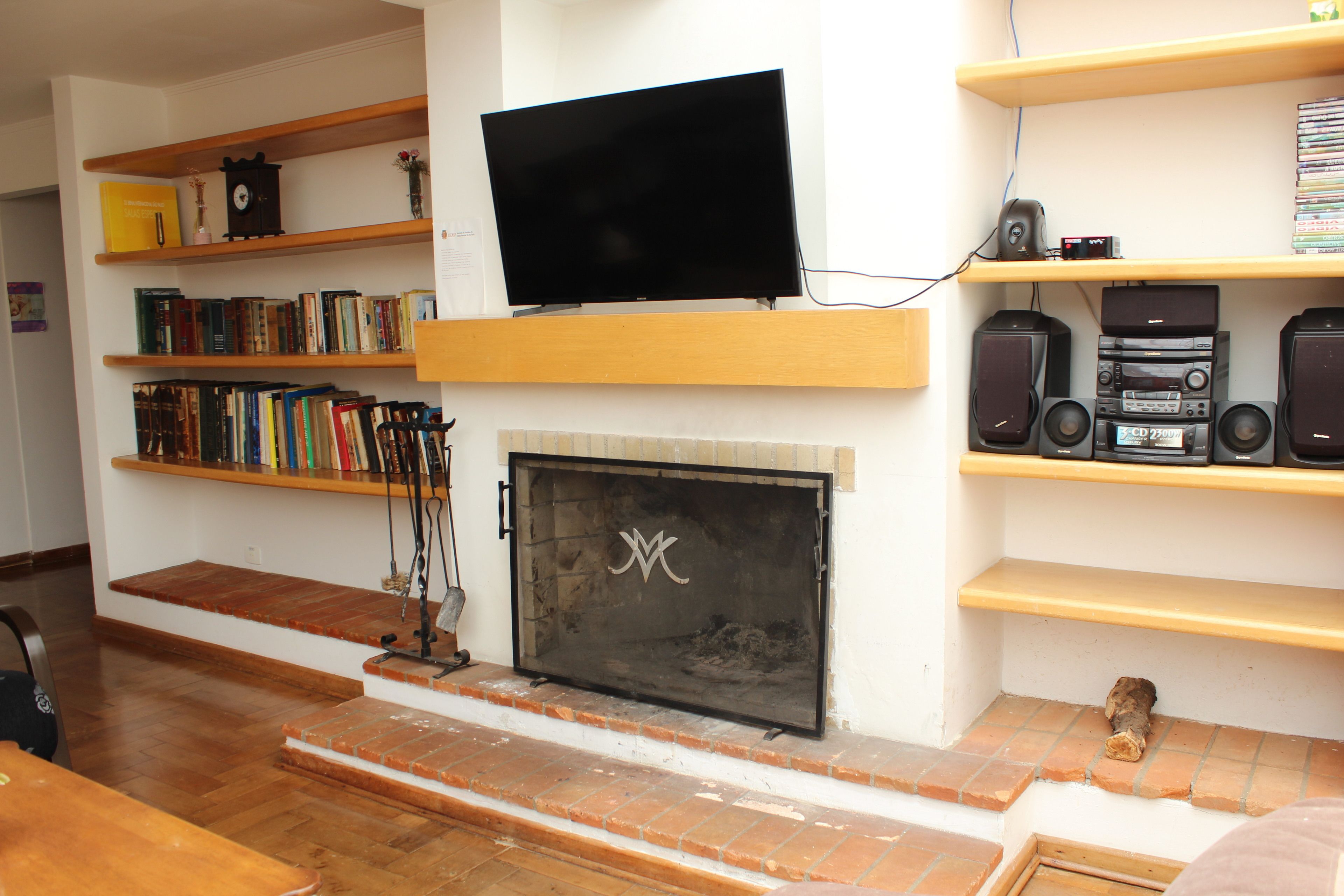 Una sala de estar con chimenea, estanterías, televisor de pantalla plana y una cafetera.