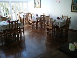 A dining area with multiple tables and chairs, wooden flooring, and a painting on the wall. - Pousada Vila Menotti (Campos do Jordão)