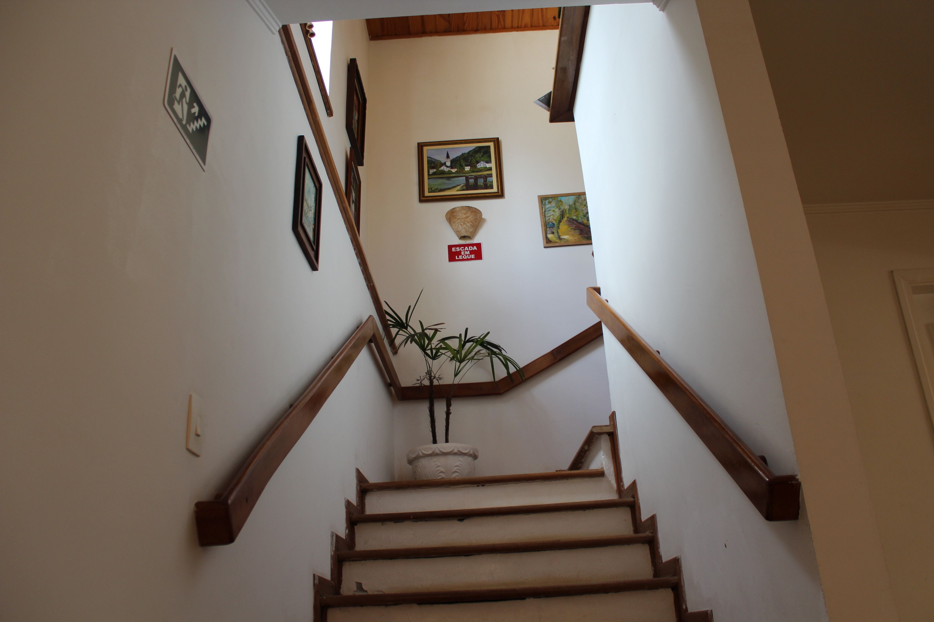 Eine Treppe mit Holzhandläufen, einem Blumentopf und gerahmten Bildern an den Wänden.