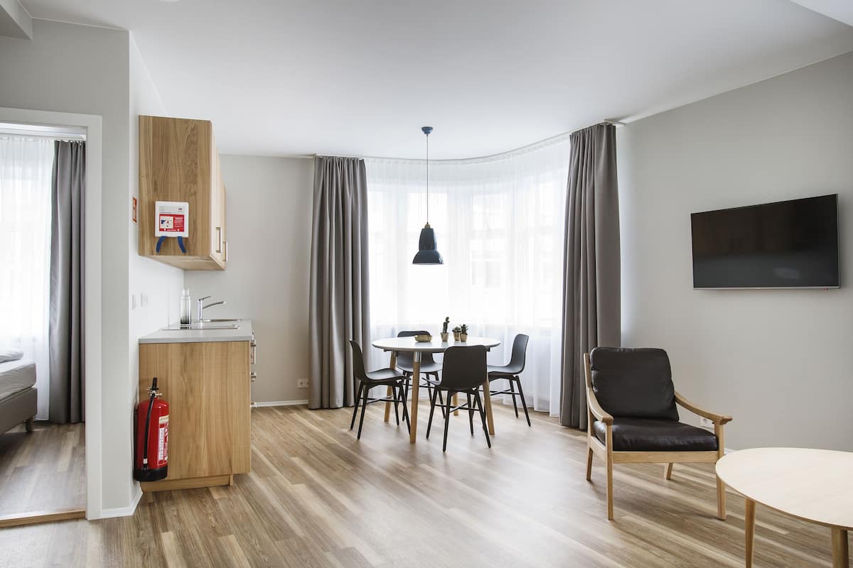 Een moderne hotelkamer met een zithoek, een flatscreen televisie, een brandblusser en een houten kast.